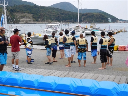 筏レースの参加者が競技ルールについての説明を受けています。 「西ノ島町Ｂ＆Ｇ海洋センター」のサポートで安全対策も万全です。